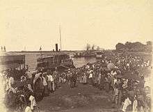 Mounted soldiers disembark surrounded by Burmese onlookers.