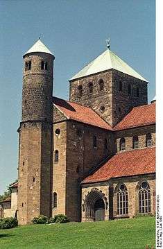 The exterior of the same church shows a short square tower with a pointed metal roof over the crossing, and a small round tower at the end of the transept.