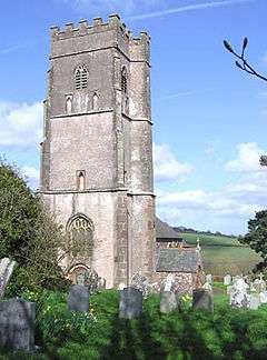 Square stone tower with gravestones in the foreground.