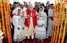 Modi unties a ceremonial red ribbon before a crowd of onlookers