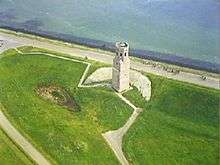 Arial photograph of a white stone tower near the shore