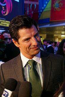 Smiling young man in brown suit, green striped shirt and green tie, being interviewed