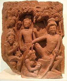 A brown stone sculpture. Rama sits on a stone under a tree (right, largest figure) with a bow in left hand and the other hand on the head of Ahaya(centre bottom), who is seated on the ground with flowers in her hand. Behind her stands Lakshamana. The leftmost figure is of Vishvamitra sitting on a stone.