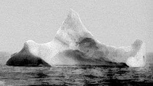 Black and white photograph of a large iceberg with three "peaks".