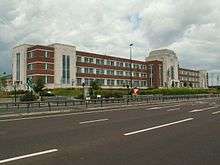 A large brick and stone Art Deco industrial building on far side of dual carriageway