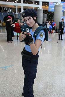Photograph of Voth in a blue police uniform pointing a toy gun at the viewer.